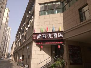 un bâtiment avec un panneau sur son côté dans l'établissement Thank Inn Plus Hotel Shanxi Taiyuan Xiaodian District Rongjun North Street High Speed Railway Station, à Taiyuan