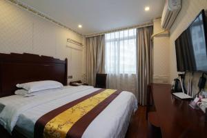 een hotelkamer met een groot bed en een televisie bij JUN Hotels Guangdong Shenzhen Yantian District Zhongying Street in Shenzhen