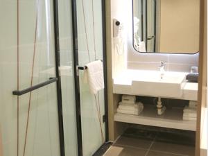 a bathroom with a sink and a mirror and a shower at Up And In Shandong Linyi Lanshan District Taisheng Square in Linyi