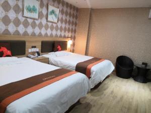 a hotel room with two beds in a room at JUN Hotels Anhui Bangbu Guzhen County Huihe Road Store in Qiaokou