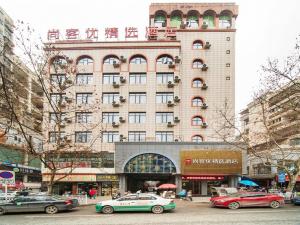 Thank Inn Plus Hotel Guizhou Zunyi Old Railway Station في زونيي: مبنى كبير فيه سيارات تقف امامه