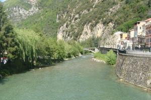 a river with a bridge next to a mountain at breil sur roya in Breil-sur-Roya