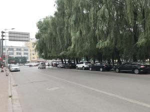 a street with cars parked in a parking lot with trees at JUN Hotels Jinzhong Yuci District Railway Station in Jinzhong