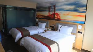 two beds in a hotel room with a painting on the wall at Thank Inn Chain Hotel Qinghai Haixi Wulan Xinghai Business Street in Kaiba