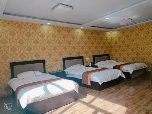 Duas camas num quarto com papel de parede amarelo em JUN Hotels Hebei Zhangjiakou Xuanhua District Railway Station Store em Zhangjiakou