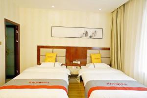 una habitación de hotel con 2 camas en una habitación en JUN Hotels Gansu Jiayuguan Jingtie District Guanghui Community, en Jiayuguan