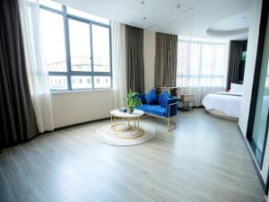 a hotel room with a bed and a blue chair and a table at Up And In Zhejiang Shaoxing Zhuji Fengqiao Town in Shaoxing