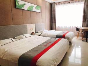 two beds in a hotel room with avertisement at JUN Hotels Shandong Binzhou Boxing County Bus Station in Binzhou