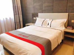 a hotel room with a large bed with red and white sheets at JUN Hotels Shandong Binzhou Boxing County Bus Station in Binzhou
