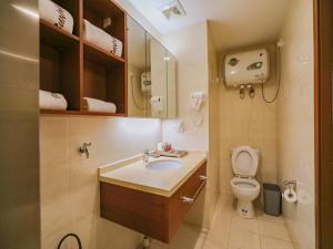 a bathroom with a sink and a toilet and a mirror at JUN Hotels Liaoning Anshan Railway Station Wanxianghui in Anshan