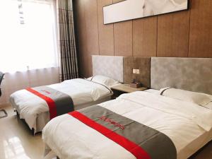 two beds in a hotel room with avertisement at JUN Hotels Shandong Binzhou Boxing County Bus Station in Binzhou