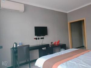 a bedroom with a bed and a tv on the wall at JUN Hotels Hebei Zhangjiakou Xuanhua District Railway Station Store in Zhangjiakou