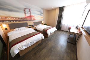 a hotel room with two beds and a painting of a stadium at Thank Inn Plus Hotel Qingdao Jiaozhou Jiaoping Road high-speed intersection in Qingdao