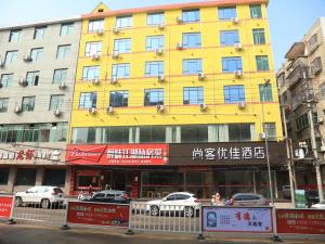 a yellow building with cars parked in front of it at Thank Inn Chain Hotel Jiangxi Fuzhou Dongxiang District High Speed ââRailway Station in Fuzhou
