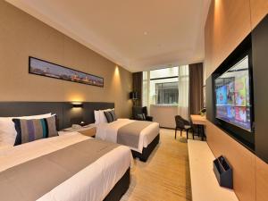 a hotel room with two beds and a flat screen tv at Lano Hotel Guangdong Heyuan Dongyuan County Administrative Avenue in Heyuan