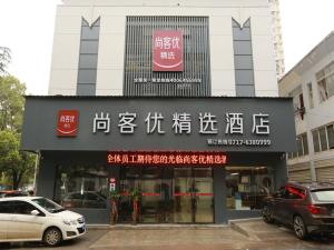 un edificio con escritura en él con coches aparcados fuera en Thank Inn Plus Hotel Yichang Free Trade Zone Development Avenue, en Yichang