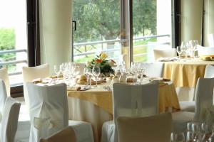 a set of tables with white chairs and wine glasses at Hotel Il Castellaccio in Piccione