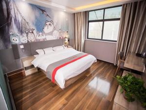 1 dormitorio con 1 cama grande y un mural de Hello Kitty en JUN Hotels Shandong Heze Development Zone Shanghai Road en Xinji