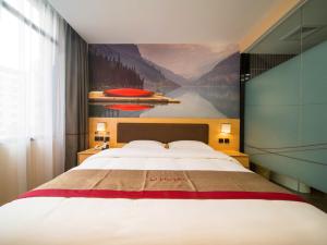 a bedroom with a large bed with a painting on the wall at Thank Inn Plus Hotel Guizhou Zunyi Old Railway Station in Zunyi