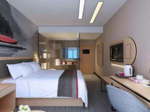 een hotelkamer met een groot bed en een bureau bij Thank Inn Chain Hotel Hebei Handan Wu'an City Bus Station in Handan