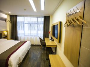 Habitación de hotel con cama, escritorio y TV. en Thank Inn Plus Hotel Yichang Free Trade Zone Development Avenue, en Yichang