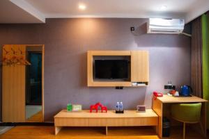 uma sala de estar com uma mesa e uma televisão na parede em JUN Hotels Hebei Hengshui Shenzhou Bus Station em Hengshui