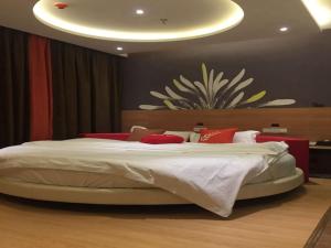 a bedroom with a large white bed with red pillows at JUN Hotels Dezhou Decheng District Xinhu Park Pedestrian Street in Dezhou