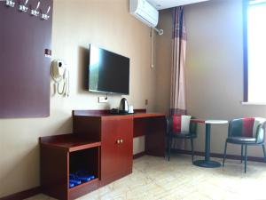 a room with a desk with a television and chairs at JUN Hotels Shanxi Lvliang Lishi District Lvliang Academy West Gate in Luliang