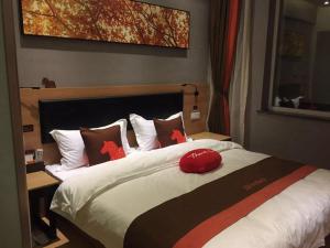 a bedroom with a bed with a red hat on it at JUN Hotels Dezhou Decheng District Xinhu Park Pedestrian Street in Dezhou +2 photos
