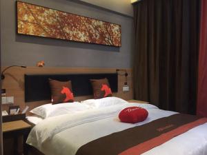 a bedroom with a large bed with a red hat on it at JUN Hotels Dezhou Decheng District Xinhu Park Pedestrian Street in Dezhou