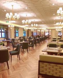 een eetkamer met tafels en stoelen en kroonluchters bij Taizhou Haiyan Jinling International Hotel in Taizhou
