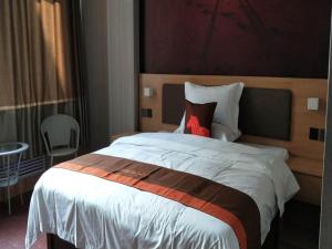 a bedroom with a large bed with a red pillow at JUN Hotels Shandong Binzhou Yangxin County Yangcheng 3rd Road in Binzhou