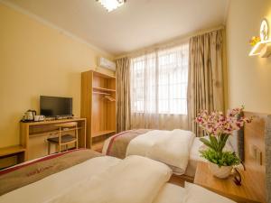 a hotel room with two beds and a television at Thank Inn Chain Hotel Yunnan Lijiang Old Town Dashuiche North Gate in Lijiang