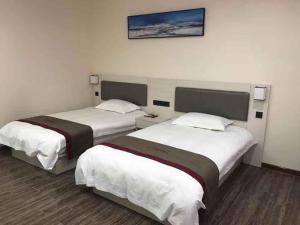 two beds in a hotel room with a picture on the wall at Thank Inn Chain Hotel Shandong Laiwu Laicheng District Changshou North Road People's Hospital in Laiwu