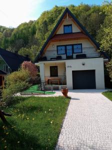 a house with a gambrel roof with a garage at Pokoje u Wojciecha in Tylmanowa