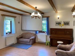a living room with a couch chair and a screen at Chalupa a apartmány Lojka in Benecko