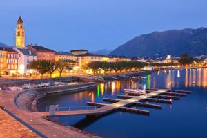 una città con barche in acqua di notte di Casa Cincillà ad Ascona
