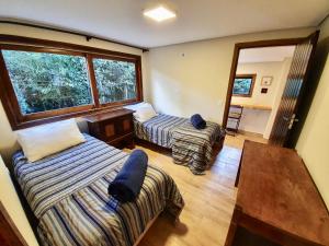 a room with two beds and a table and a window at Empório reserva da serra - Opções de chalés e Hidromassagem in Campos do Jordão