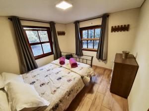 um quarto com uma cama com sapatos cor-de-rosa em Empório reserva da serra com área lazer natureza e excelente localização em Campos de Jordão