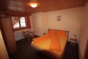1 dormitorio con cama con almohadas de color naranja y mesa en Haus Vallaster, en Gaschurn