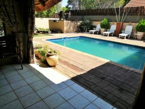 a swimming pool with a wooden deck next to a patio at Safari Guesthouse in Vryburg