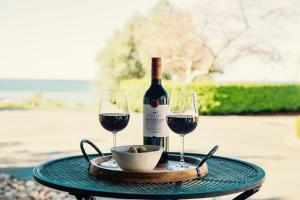 a bottle of wine and two glasses on a table at Olive Hill Guest Lodge in Napier