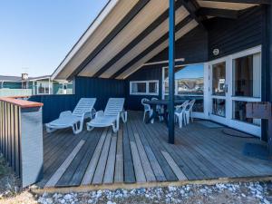 eine Holzterrasse mit Stühlen und einem Tisch darauf in der Unterkunft Bright Dune View Cottage-By Traum in Bjerregård