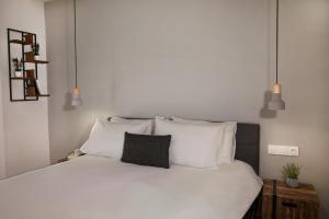 um quarto com uma cama com lençóis brancos e almofadas em Central Comfy Modern Flat 2 bedrooms 2 bathrooms em Atenas