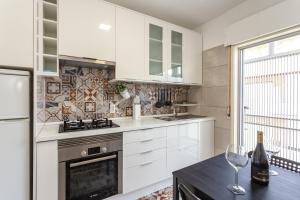 Una cocina con gabinetes blancos y una mesa con copas de vino. en Magic Theatre Faro Center, en Faro
