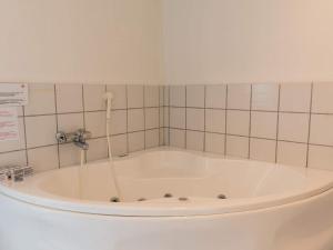 uma banheira num quarto com uma parede em azulejo em Holiday home Hvide Sande LXXV em Bjerregård