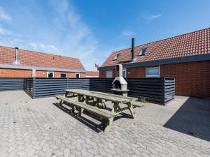 a wooden picnic table in front of a building at 6 person holiday home in Hvide Sande in Bjerregård