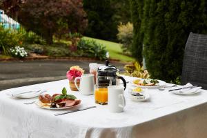 a white table with plates of food and orange juice at A view of Mount Warning in Uki