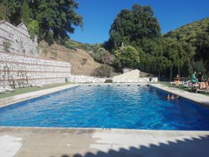 une piscine d'eau bleue en face d'une montagne dans l'établissement Casas Rurales El Viejo Castaño - Valle Del Genal, à Pujerra