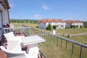 einen Balkon mit weißen Stühlen, einem Tisch und einem Haus in der Unterkunft Ferienwohnung "Möwe" im Ferien-Resort Rügen in Sagard